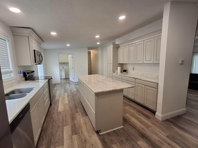 kitchen with stainless steel appliances, dark wood-style flooring, baseboards, a kitchen island, and recessed lighting
