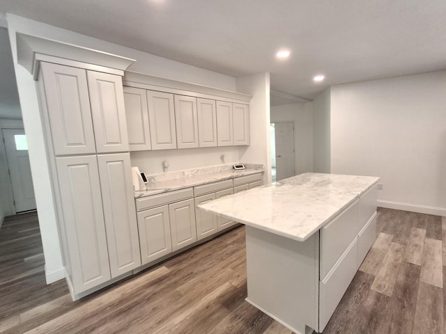 kitchen featuring light stone countertops, wood finished floors, recessed lighting, and a kitchen island
