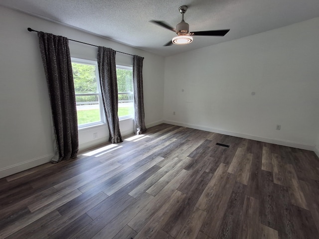spare room with dark wood-style flooring, a textured ceiling, baseboards, and a ceiling fan