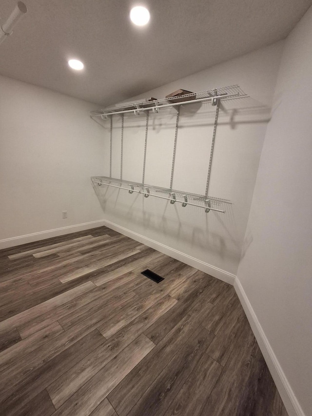 spacious closet with dark wood-style flooring and visible vents