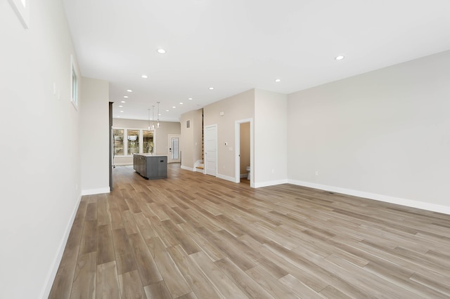 unfurnished living room with light wood-type flooring, baseboards, and recessed lighting