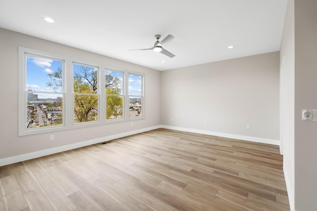 empty room featuring baseboards, a ceiling fan, and light wood-style floors