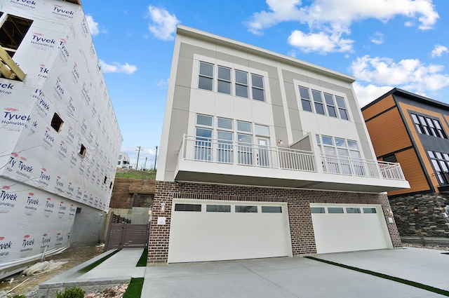 view of front of house with concrete driveway, stucco siding, brick siding, and a garage