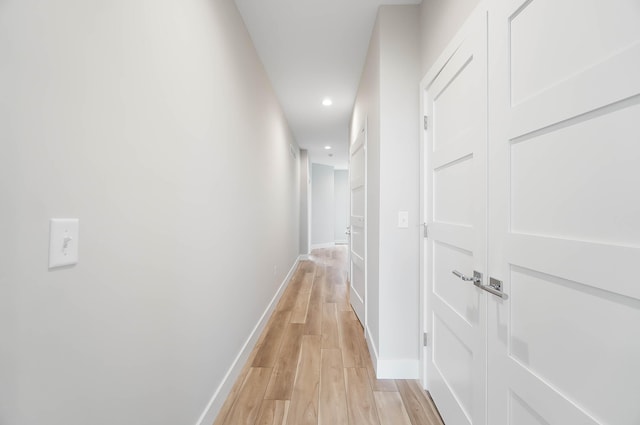 hallway featuring light wood finished floors, baseboards, and recessed lighting