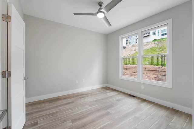 spare room featuring a ceiling fan, baseboards, and light wood finished floors