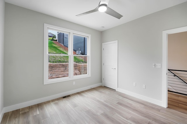 unfurnished room with light wood-type flooring, visible vents, baseboards, and a ceiling fan