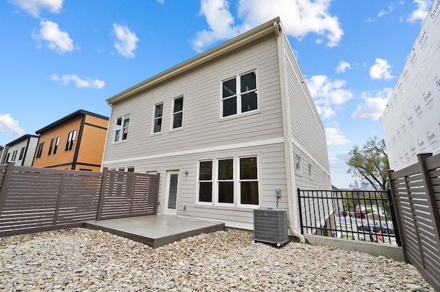 rear view of property featuring central air condition unit, a patio area, and a fenced backyard