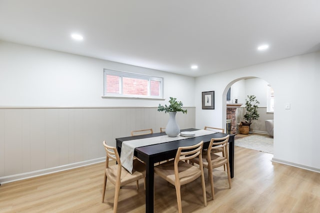 dining area with light wood-style floors, wainscoting, arched walkways, and recessed lighting