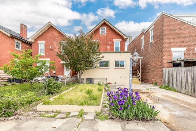 rear view of property featuring brick siding and fence