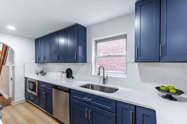 kitchen with arched walkways, stainless steel appliances, blue cabinets, and a sink