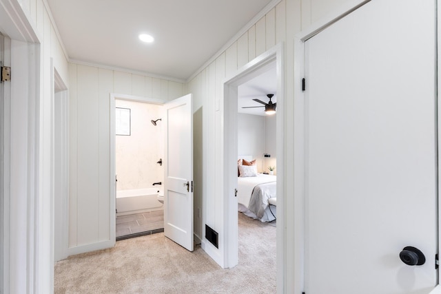 corridor featuring crown molding and light carpet