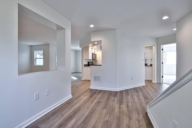 unfurnished living room with wood finished floors, baseboards, and recessed lighting
