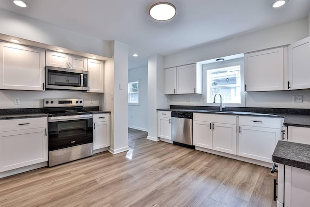 kitchen with appliances with stainless steel finishes, a sink, healthy amount of natural light, recessed lighting, and white cabinets