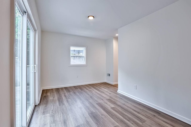spare room featuring wood finished floors, healthy amount of natural light, and baseboards