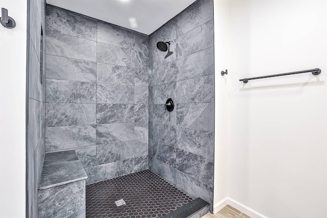 full bath with a tile shower and baseboards