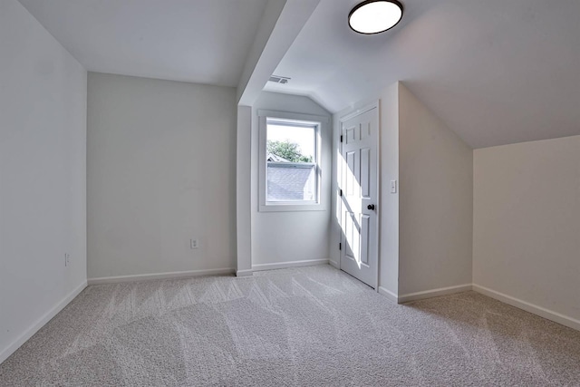 additional living space featuring lofted ceiling, light carpet, and baseboards