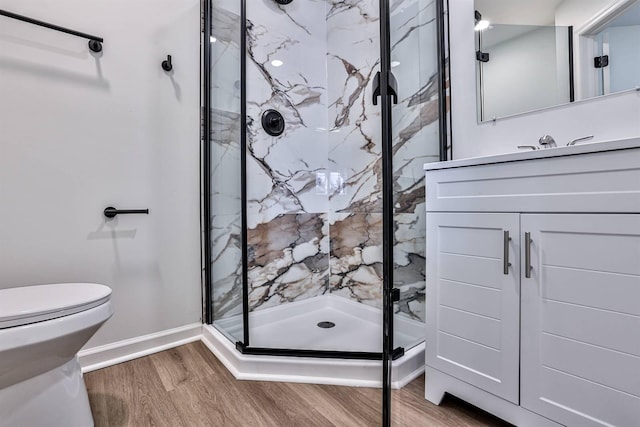 full bath with wood finished floors, a marble finish shower, vanity, baseboards, and toilet