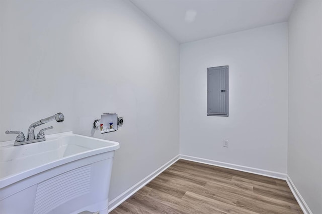 clothes washing area featuring electric panel, washer hookup, light wood-style floors, and baseboards