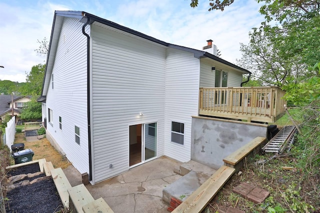 back of house featuring a chimney, a patio area, and a wooden deck