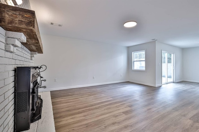 unfurnished living room featuring wood finished floors, a fireplace, and baseboards