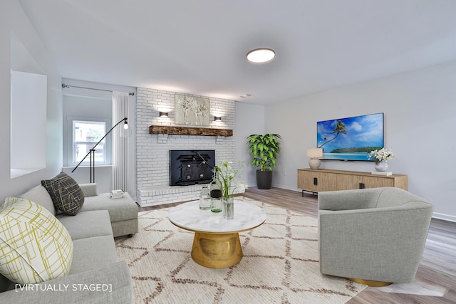 living room with wood finished floors, baseboards, and a fireplace