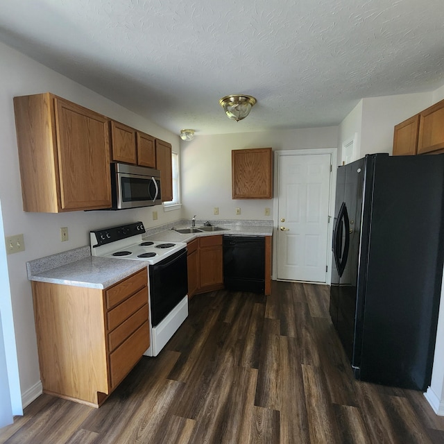 kitchen featuring black appliances, dark wood-type flooring, brown cabinetry, light countertops, and a sink