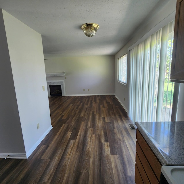 unfurnished living room with dark wood-type flooring, baseboards, and a fireplace