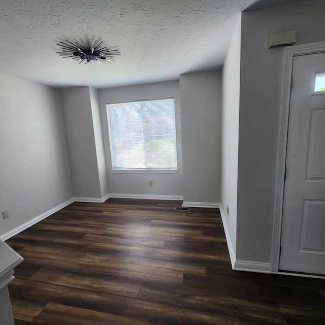 spare room with wood finished floors, baseboards, and a textured ceiling