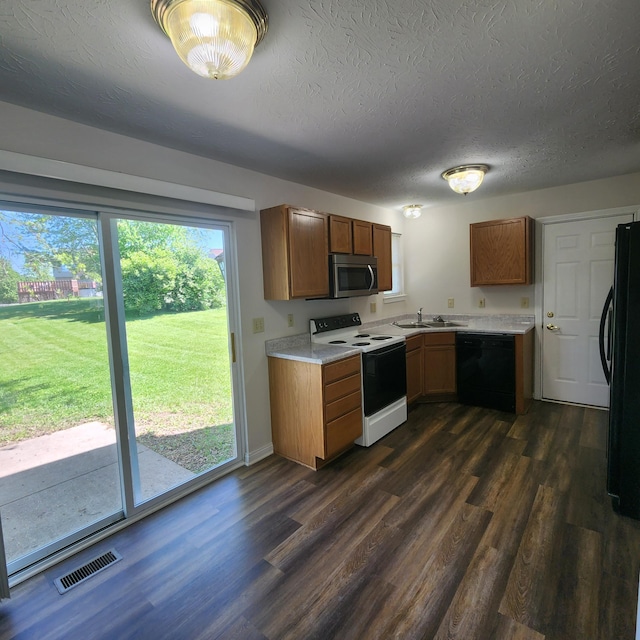 kitchen with black appliances, a sink, dark wood finished floors, light countertops, and a textured ceiling