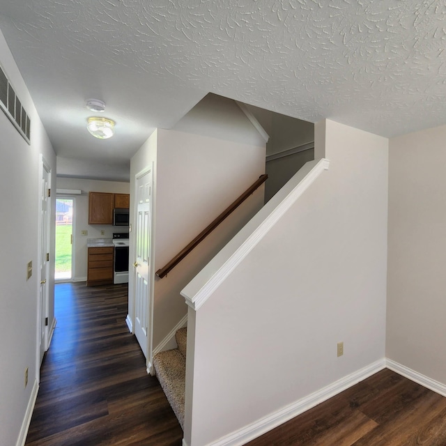 stairs featuring wood finished floors, baseboards, and a textured ceiling