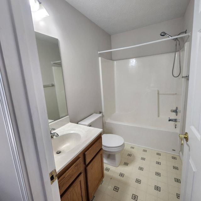 bathroom with toilet, vanity,  shower combination, tile patterned flooring, and a textured ceiling