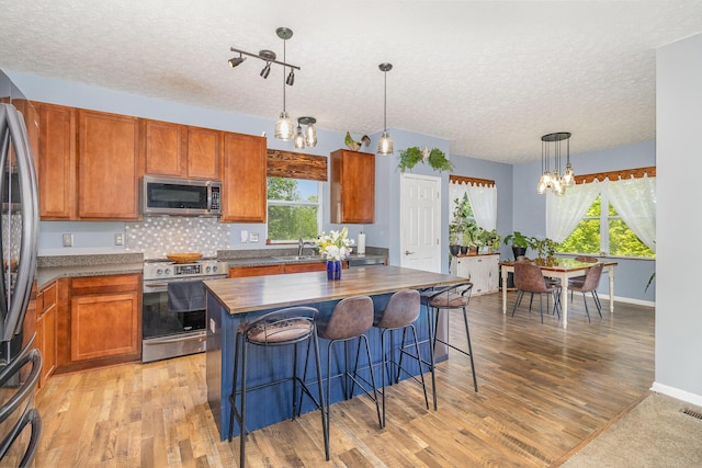 850 Stablewatch Dr, Independence, KY 41051 - kitchen with stainless steel appliances, a chandelier, a textured ceiling, a sink, and brown cabinets