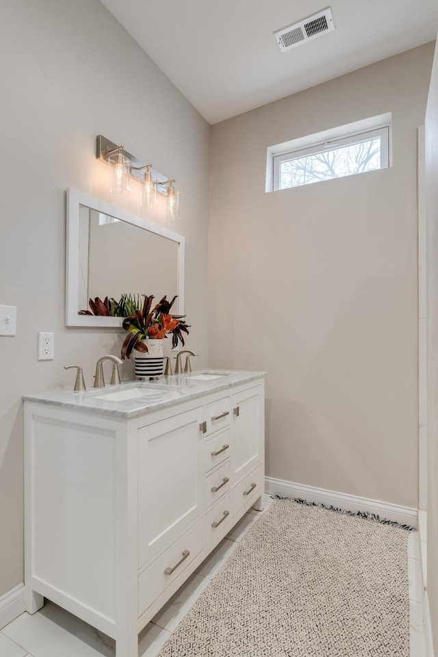 bathroom featuring double vanity, tile patterned flooring, and baseboards
