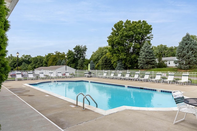 community pool featuring fence, a patio, and view of scattered trees