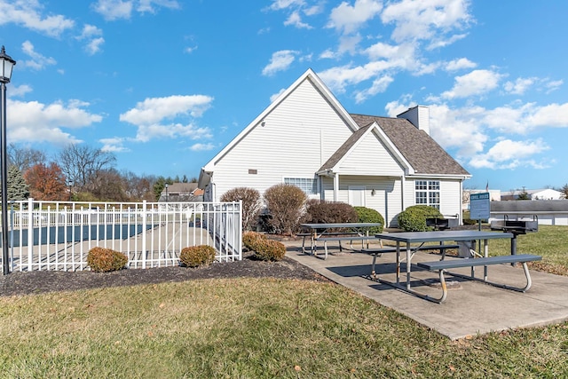 view of side of property featuring a patio, a chimney, and a shingled roof