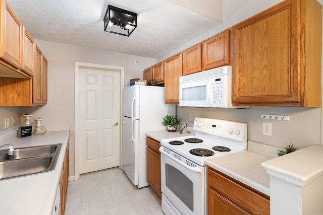 kitchen with white appliances, a sink, light countertops, and brown cabinets
