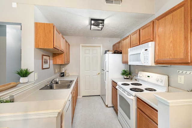 kitchen featuring white appliances, a sink, light countertops, light floors, and a textured ceiling