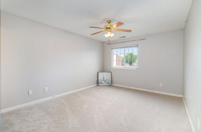 carpeted empty room featuring ceiling fan and baseboards