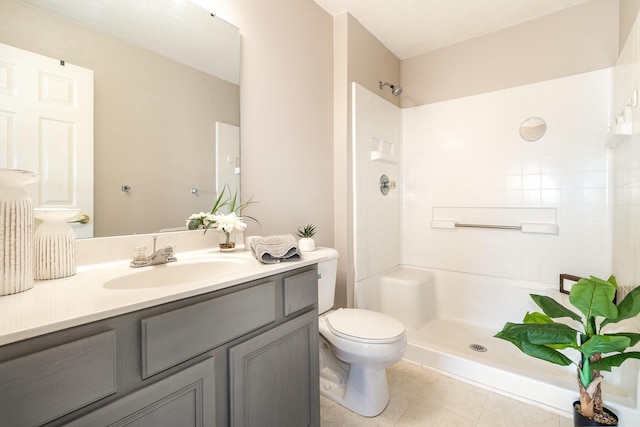 bathroom featuring toilet, a shower, vanity, and tile patterned flooring
