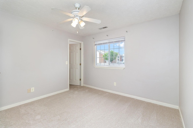 unfurnished room with light carpet, baseboards, ceiling fan, and a textured ceiling