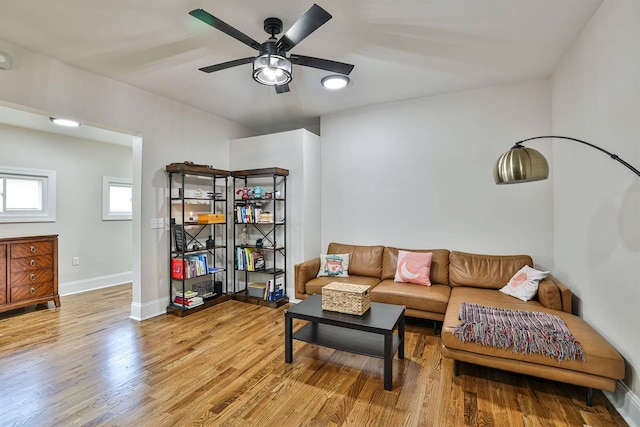 living area featuring wood finished floors, a ceiling fan, and baseboards