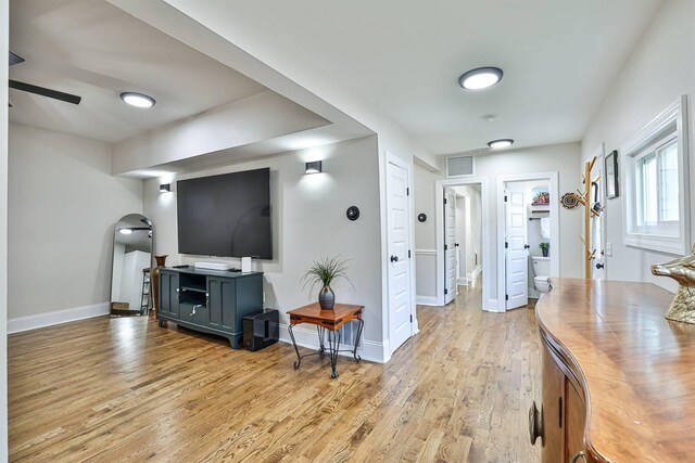 living room with light wood-style flooring, baseboards, arched walkways, and ceiling fan