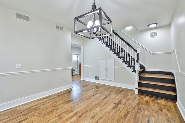 stairway with a chandelier, wood finished floors, and baseboards