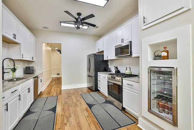 kitchen featuring stainless steel appliances, a sink, beverage cooler, tasteful backsplash, and a ceiling fan