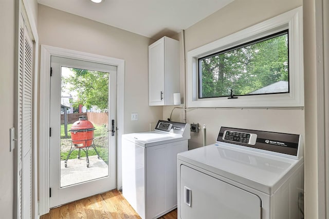 laundry area with cabinet space, washer and dryer, plenty of natural light, and light wood-type flooring