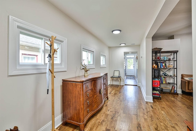 corridor featuring light wood finished floors and baseboards