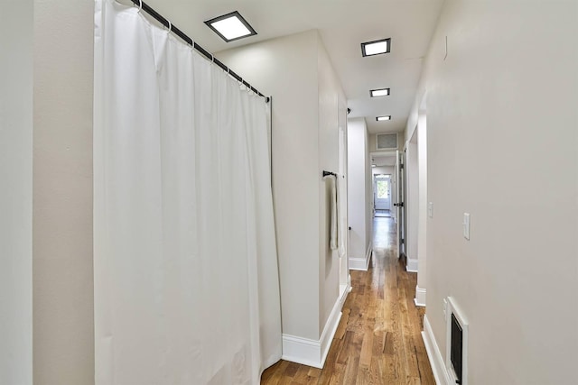 hallway featuring wood finished floors and baseboards