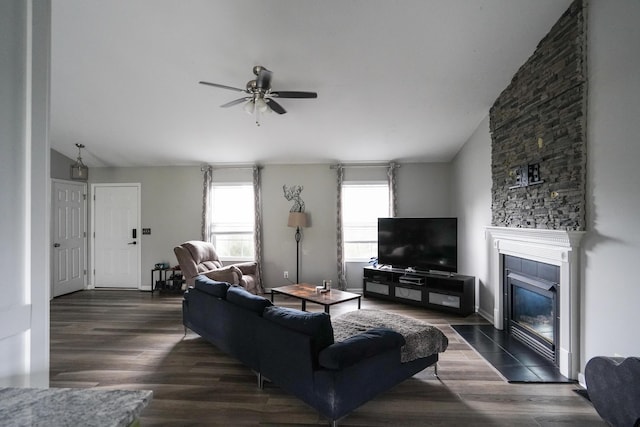 living area with ceiling fan, vaulted ceiling, dark wood finished floors, and a tile fireplace