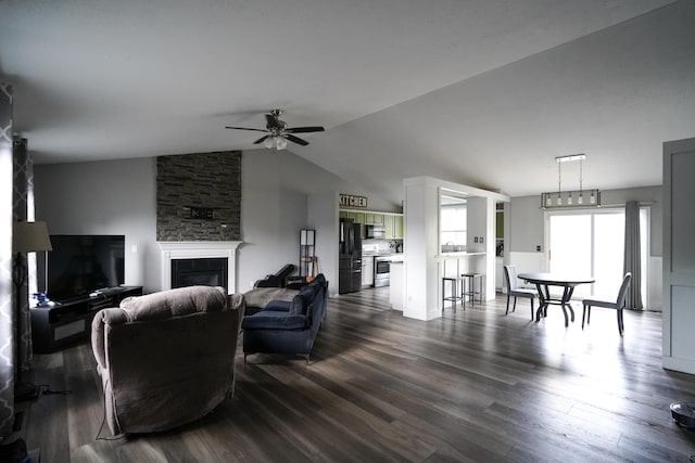 living room with a ceiling fan, a stone fireplace, dark wood-style floors, and lofted ceiling