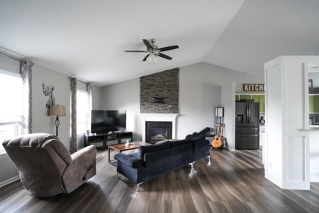 living area with ceiling fan, dark wood-type flooring, lofted ceiling, and a stone fireplace
